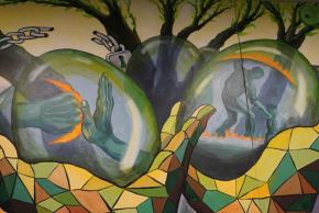 Close-up of mural featuring a pair of colorful hands cradling transparent eggs with scenes inside.