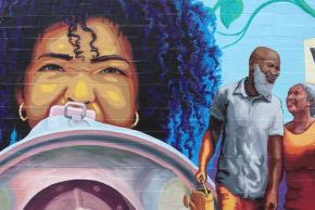 Close-up of mural at the Marcus Garvey Apartments featuring a young woman speaking into a megaphone.