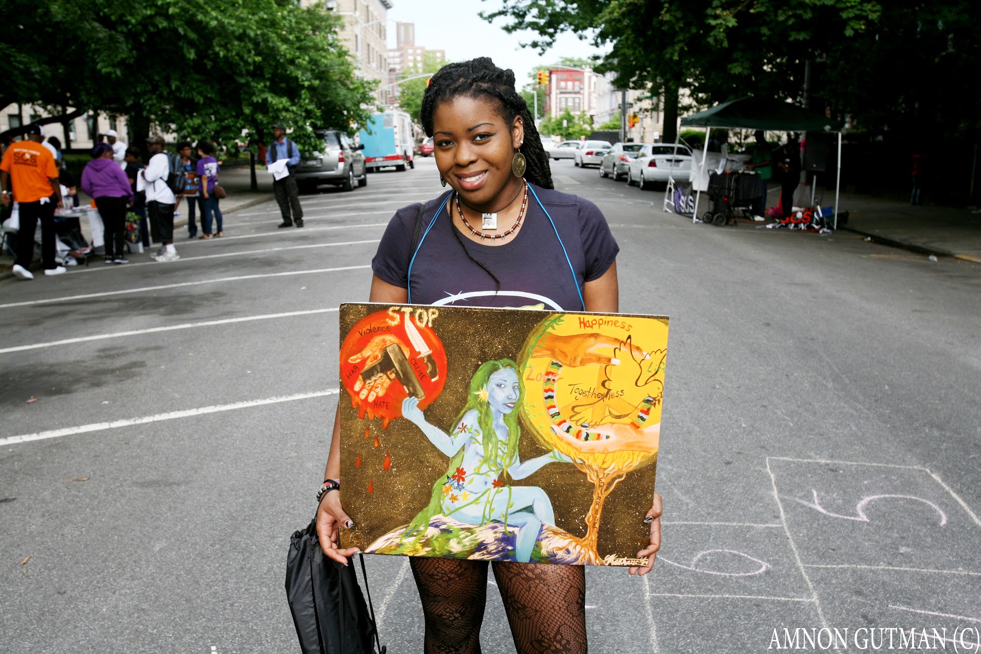 Young person holds their artwork on the street.