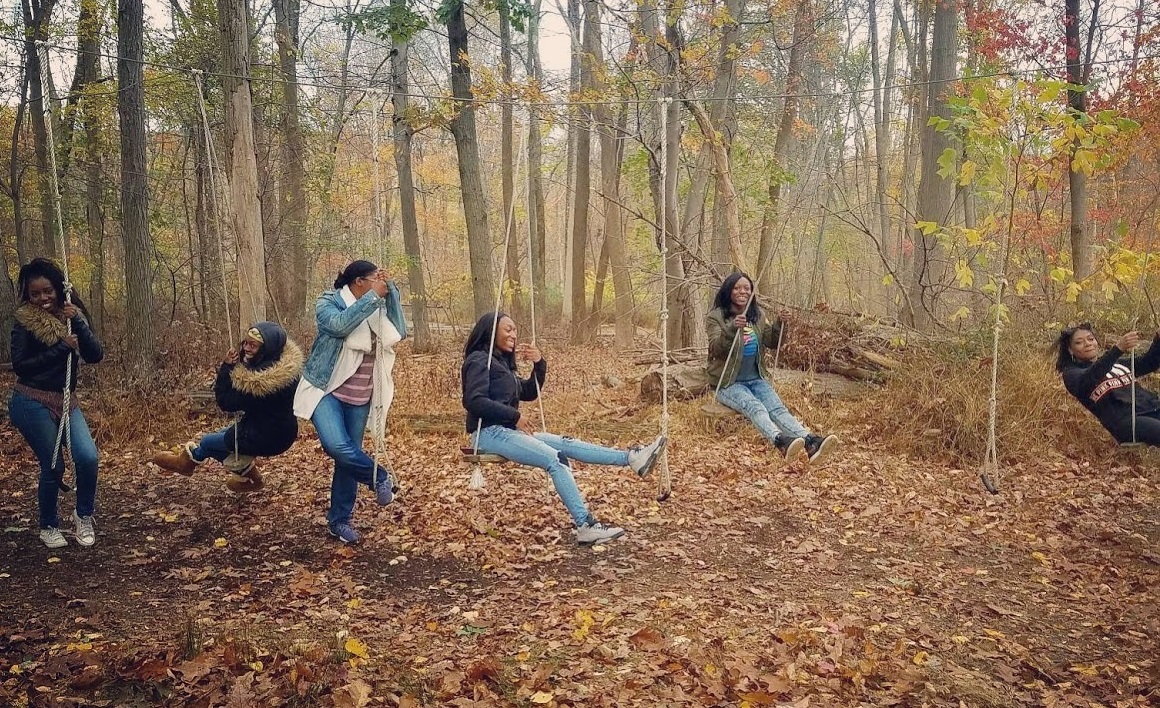 Young people on swings on a fall day. Identity based initiatives gives youth space to explore their identities.