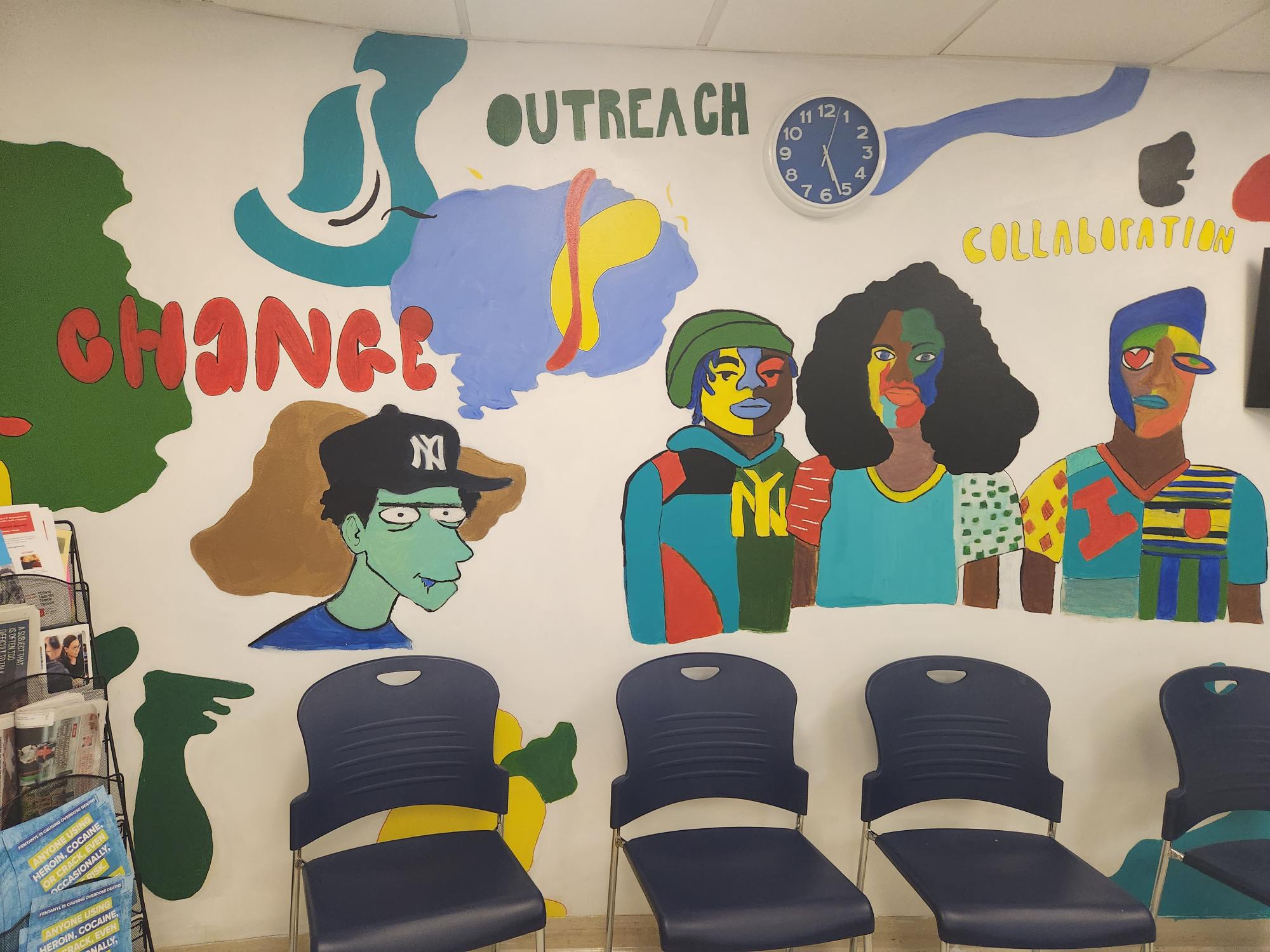 Indoor illustration on wall of people made up of colorful patches of yellow, green, brown, blue, and red with words "Change," "Outreach," and "Collaboration" in bubble letters.