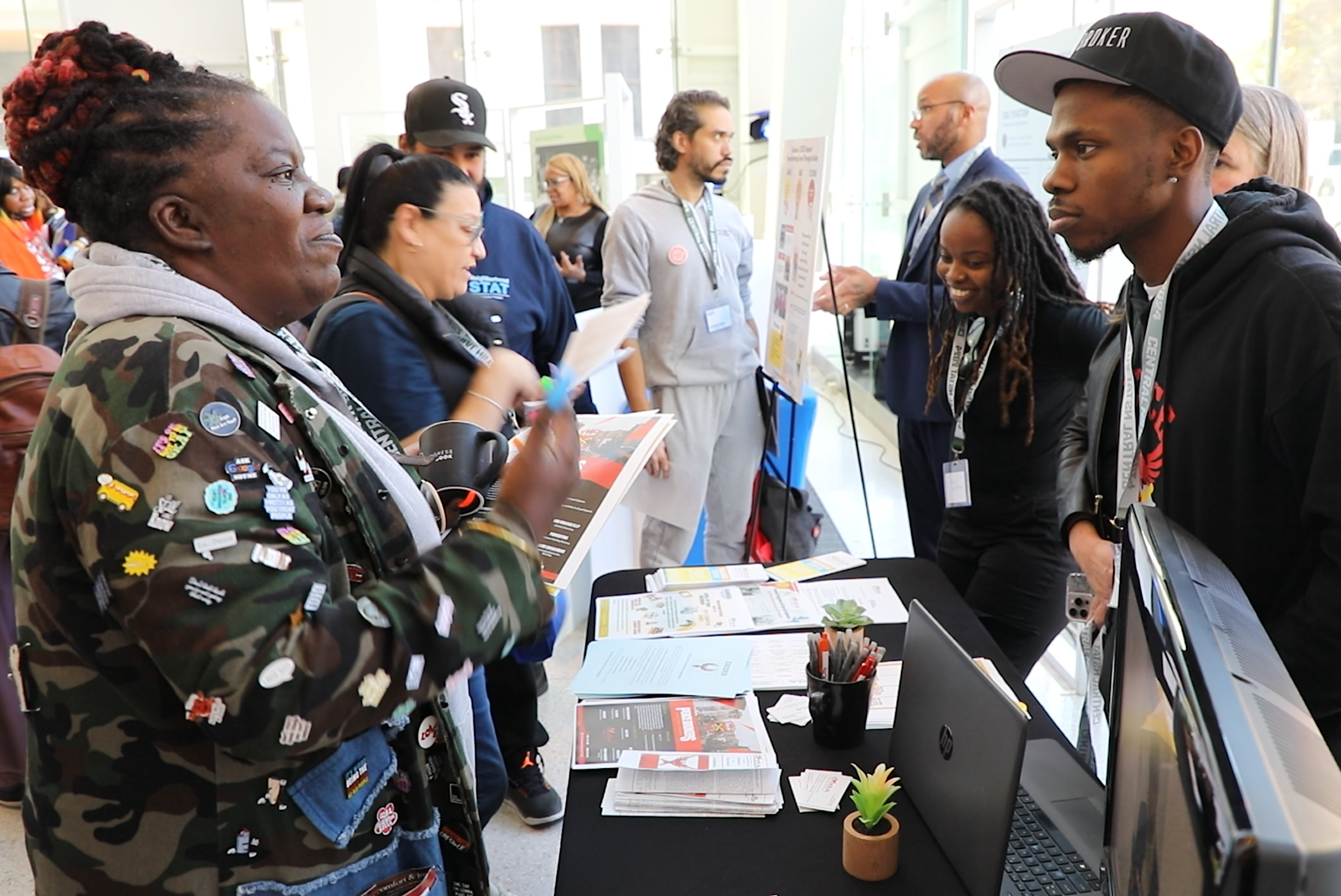 People conversing indoors over printed informational materials at Community Policy Breakfast in Brooklyn.