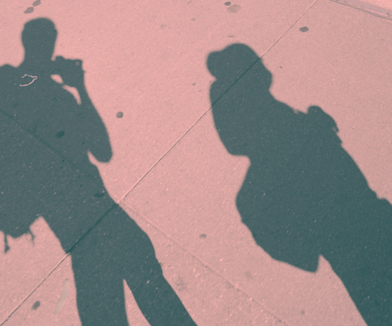 Two shadows of teenage schoolkids cast on a sidewalk