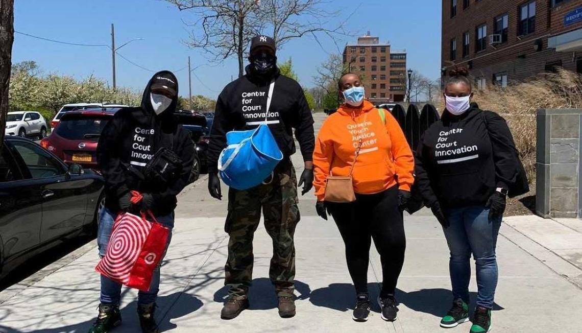 4 people with the Center for Court Innovation sweatshirts standing on a street corner with masks, gloves, and bags ready to work in the community