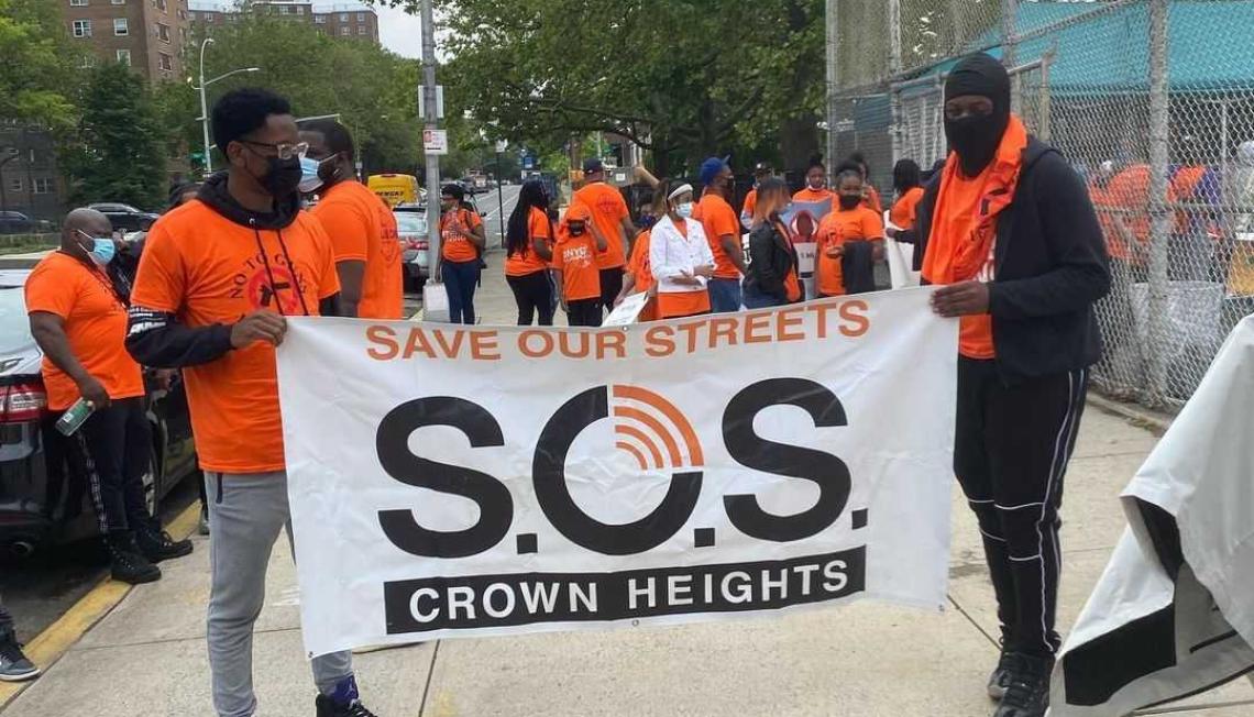 Save our Streets banner is displayed by two men at a march in Brooklyn.