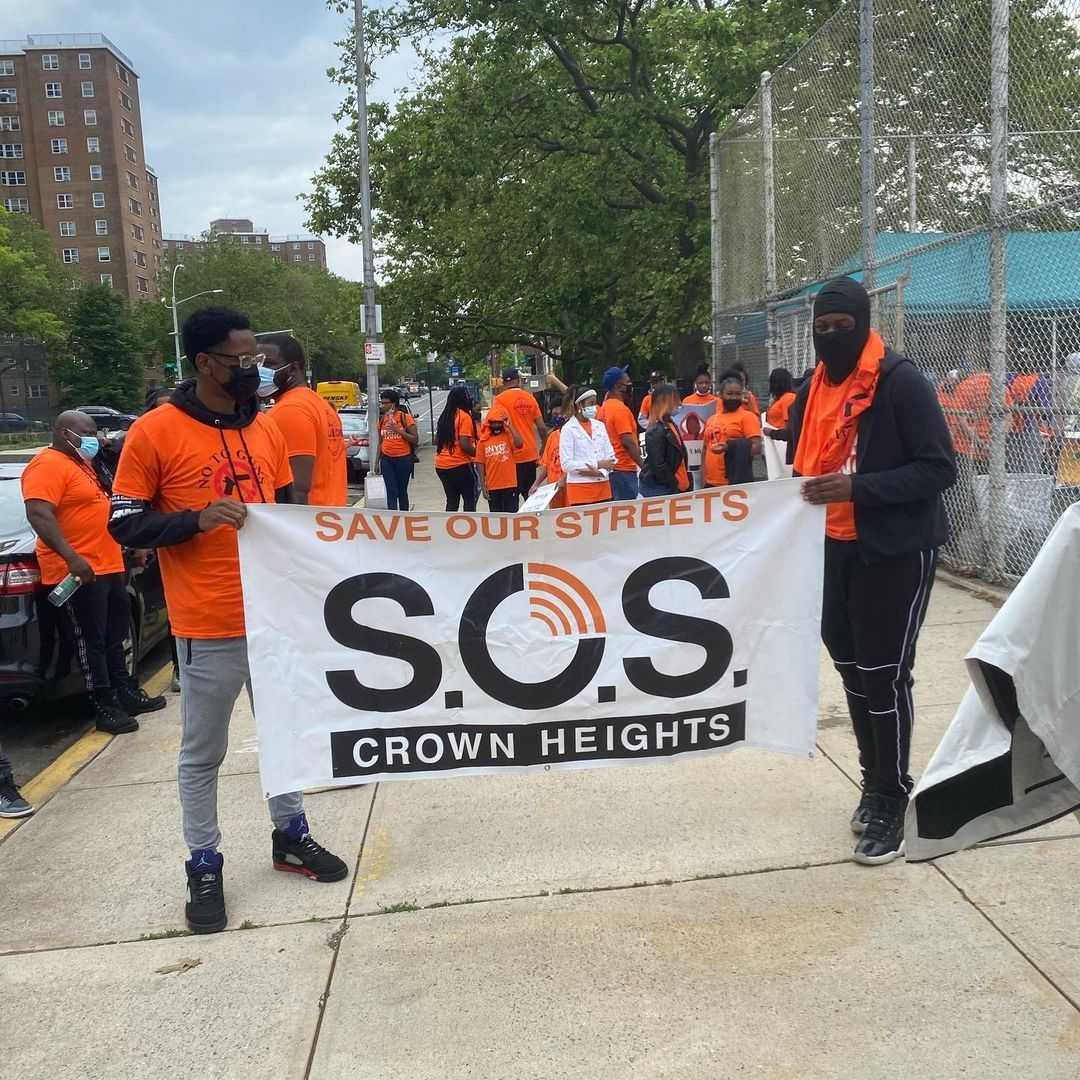 Save our Streets banner is displayed by two men at a march in Brooklyn.