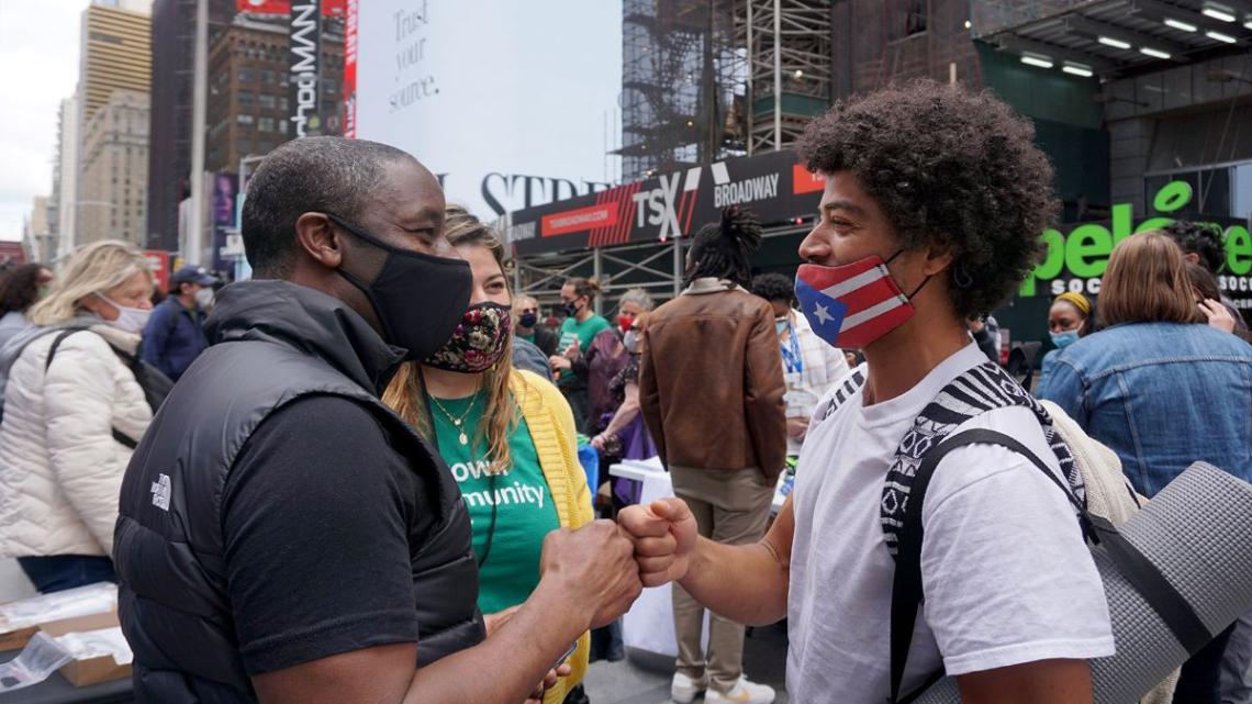 Two men fist bump, smiling, at a resource fair providing services and connections to people who need them