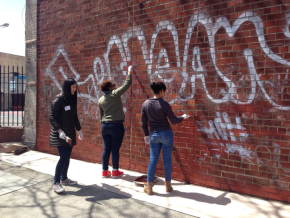 Community youth work together to remove graffiti.