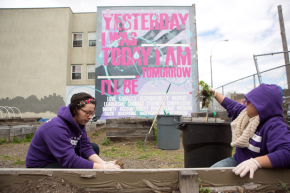 Planting new trees in a community garden in the shade of a mural created by Groundswell in collaboration with the Brownsville Community Justice Center.