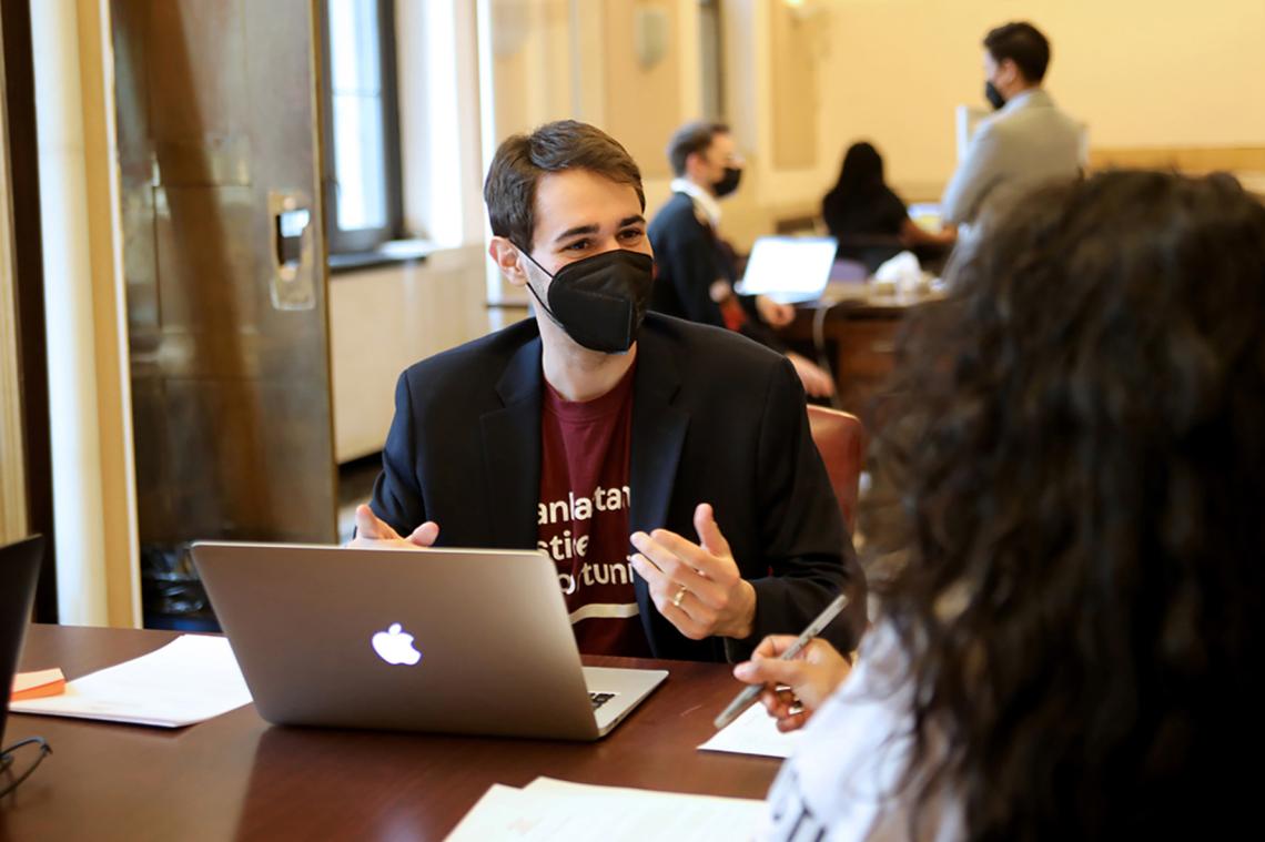 Center/MJO staff member sitting at a desk with laptop describing Manhattan Justice Opportunities