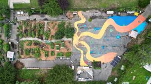 Overhead shot of Queens Community Justice Center mural next to garden featuring yellow and orange squiggly lines.