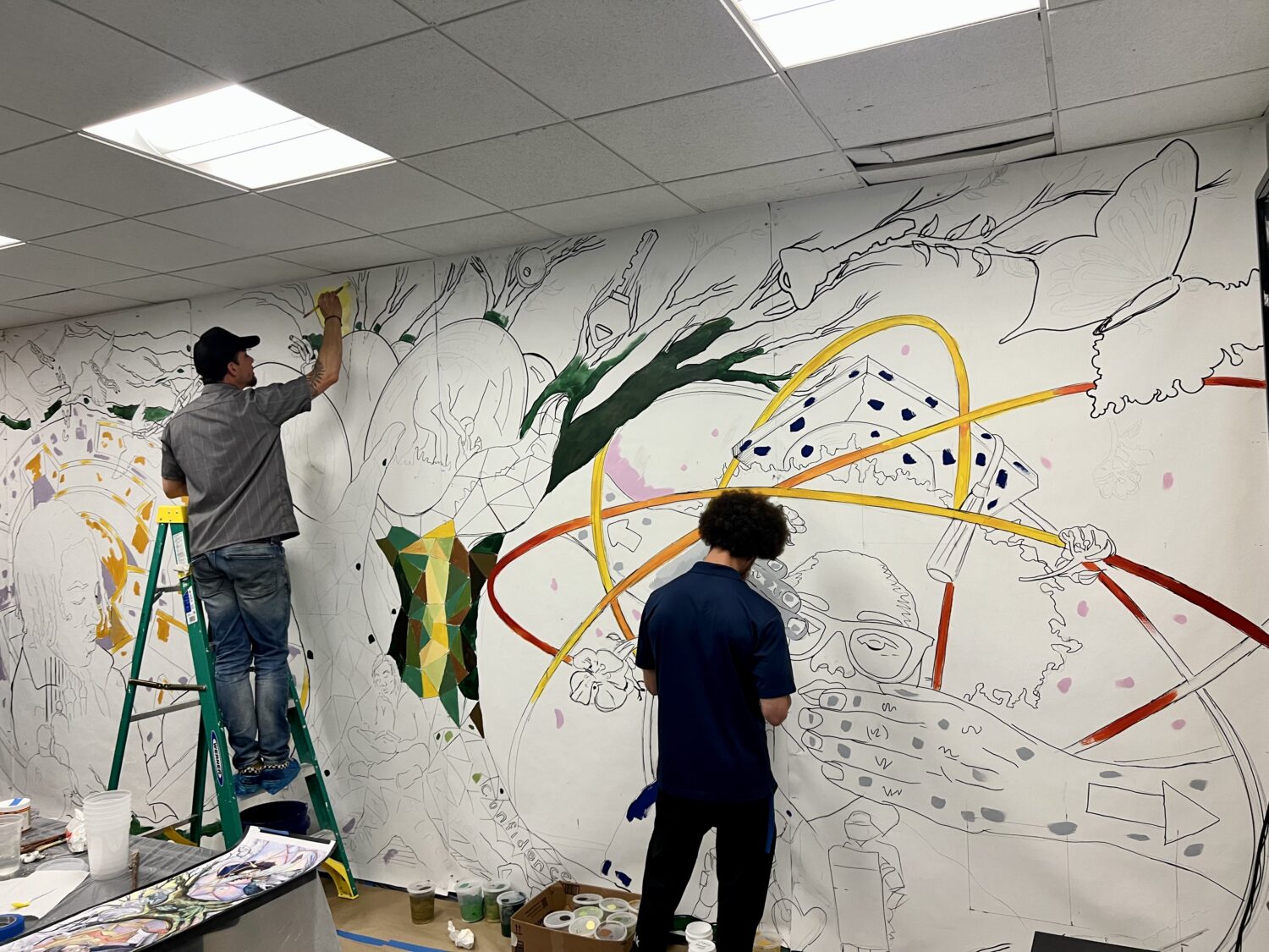 Two Brooklyn Justice Initiatives workers paint a wall mural