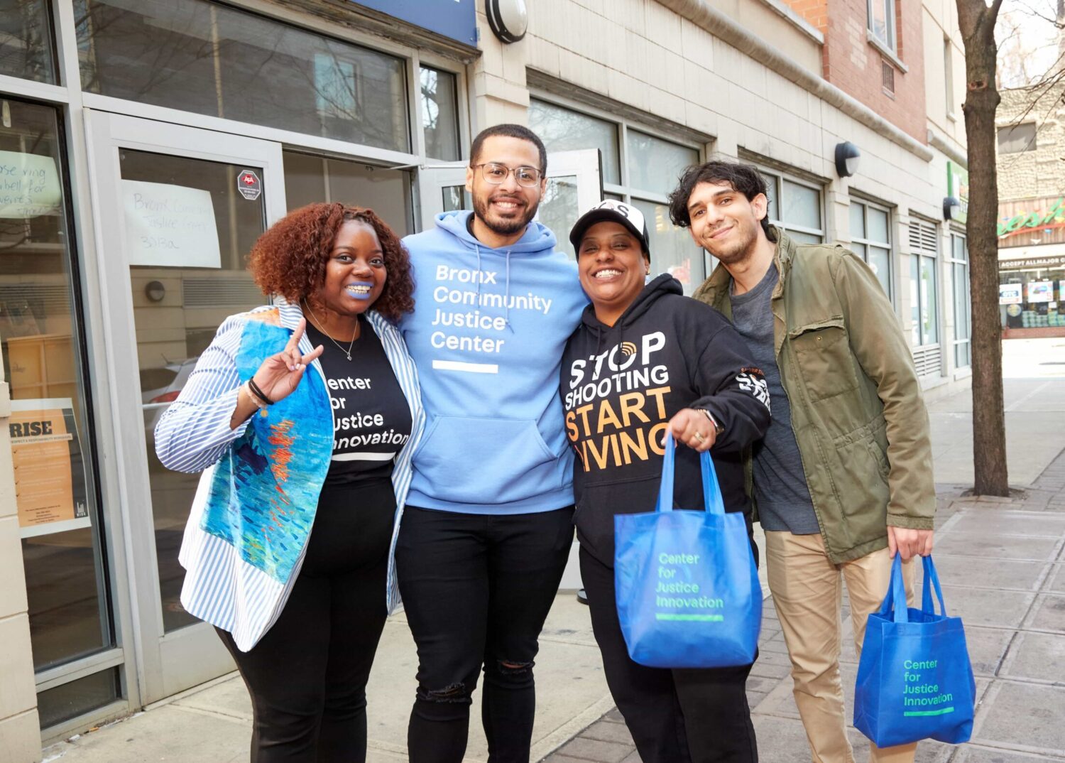 Staff from different sites embracing in front of Bronx Community Solutions.