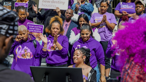 Women and men dressed in purple clapping in an anti-domestic violence rally hosted by the RISE Project