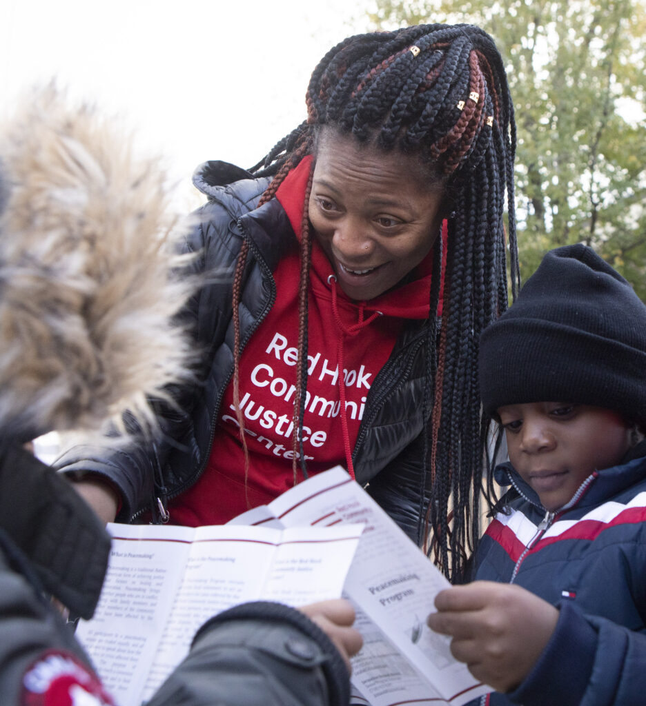 Two people standing side by side bend over a garden, watering plants.