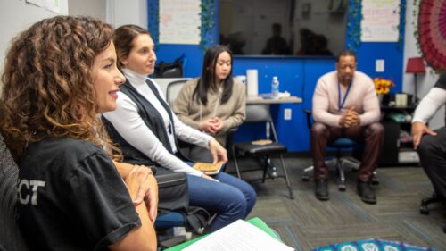 Women and men having a discussion around a semi-circle in carpeted room at Bronx Community Solutions