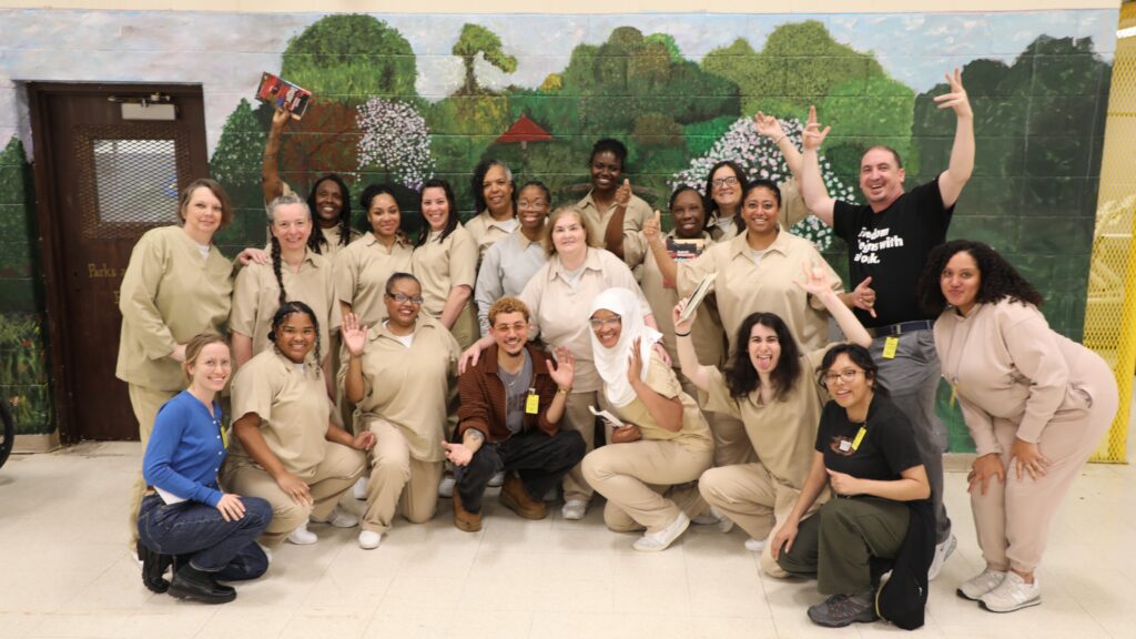 Freedom Reads and Center for Justice Innovation teams pose smiling with Inside Literary Prize judges in front of mural featuring painted trees at Edna Mahan Correctional Facility.