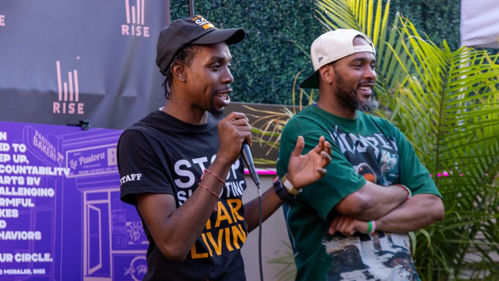 Two men speak at Men Rising launch event holding a microphone.