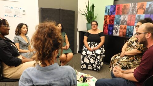 Seven people from our restorative justice team sit in a circle around a tapestry with various objects and trinkets.