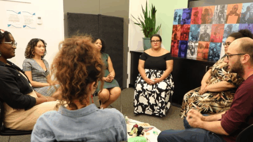 Seven people from our restorative justice team sit in a circle around a tapestry with various objects and trinkets.