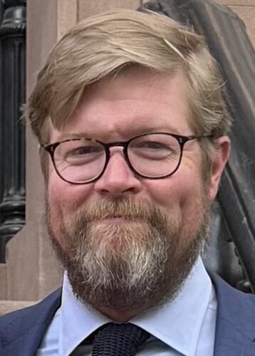 Headshot of Adam Durrett in a suit