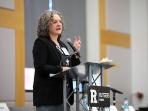 Courtney Bryan speaks into a microphone at a podium with Rutgers University label.