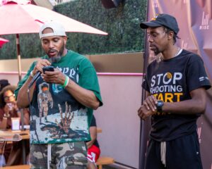 Two men stand together at our Men Rising launch event while one speaks into a microphone reading from his phone