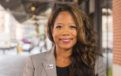 Twyla Carter, Attorney-in-Chief and CEO of the Legal Aid Society, smiles outdoors in grey jacket over black shirt with 
