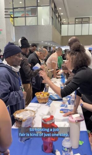 Staff and attendees speaking over a table at a job fair.