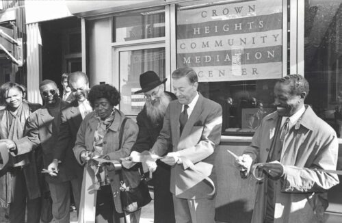 Group of people cutting the ribbon for the opening of Crown Heights Community Mediation Center.