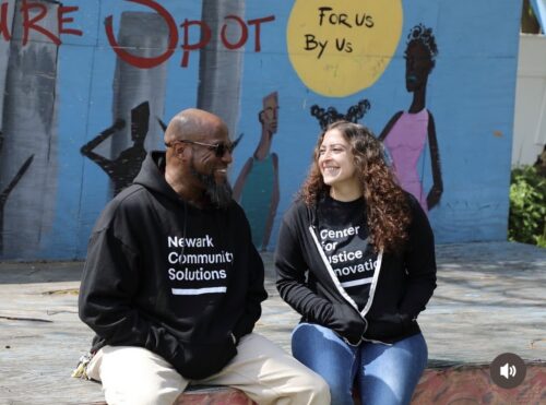 2 staff members sit smiling in conversation